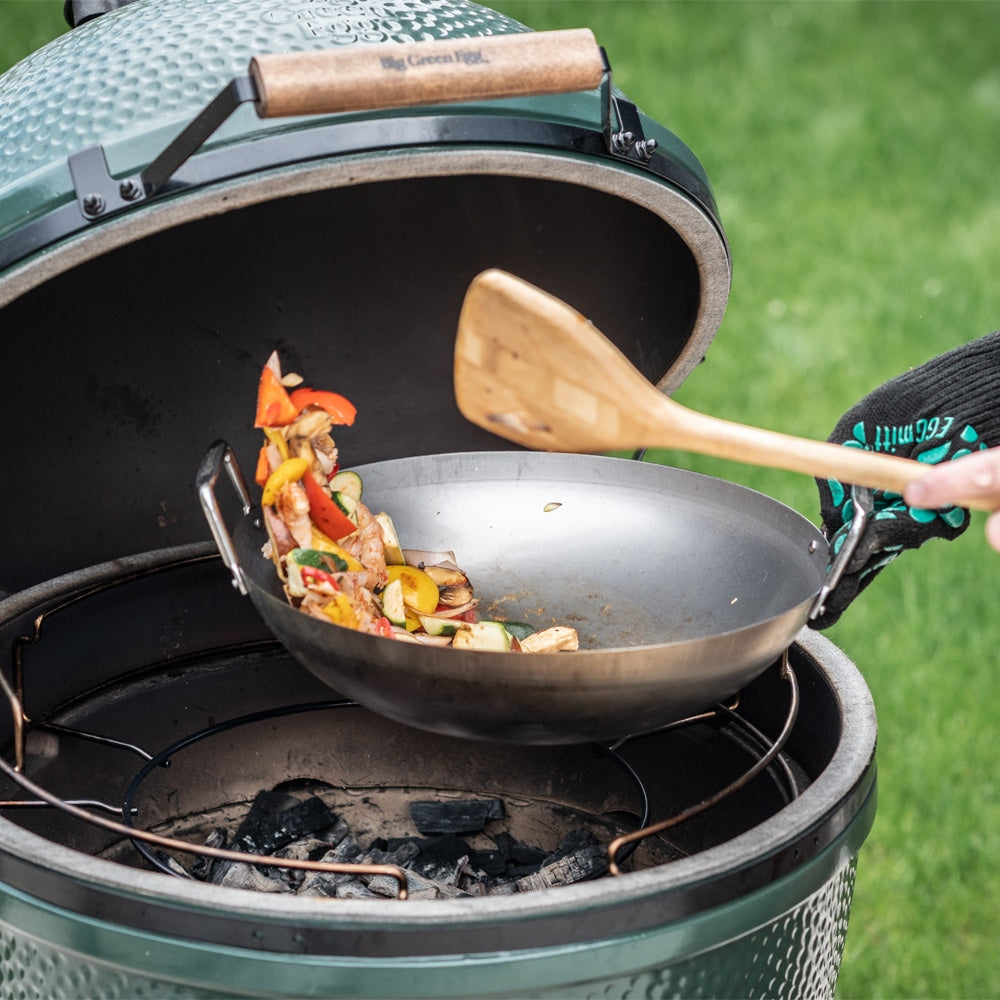 Zöldséges wokétel grillezés közben Big Green Eggben, színes paprika, hús és zöldség keverése fa spatulával