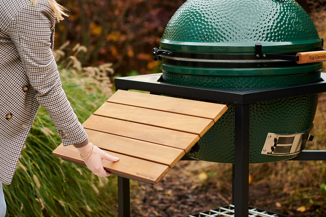 Oldalsó teakfa burkolat Big Green Egg kültéri grillasztalon, természetes kerti háttérrel