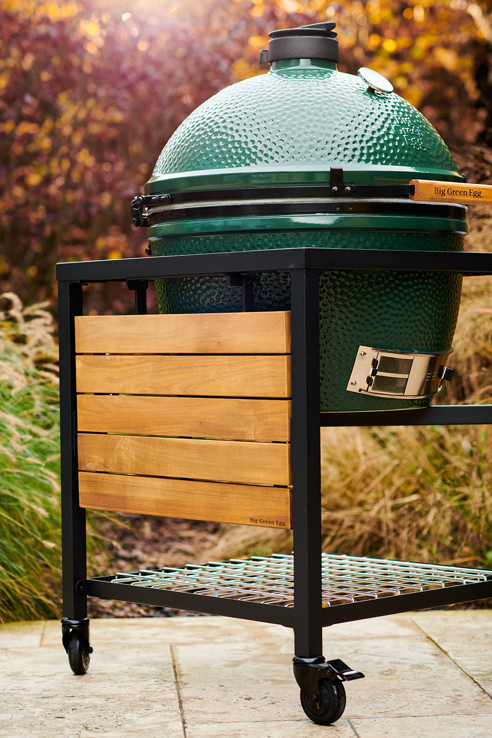 Big Green Egg grillhez rögzített teakfa lehajtható oldalpolc őszi kültéri környezetben