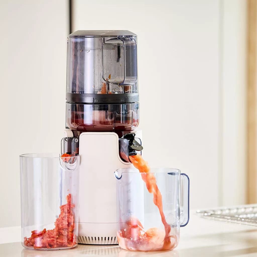 Hurom E50ST slow juicer működés közben – gyümölcslé és rost külön gyűjtőedénybe folyik, tiszta juice eredménnyel
