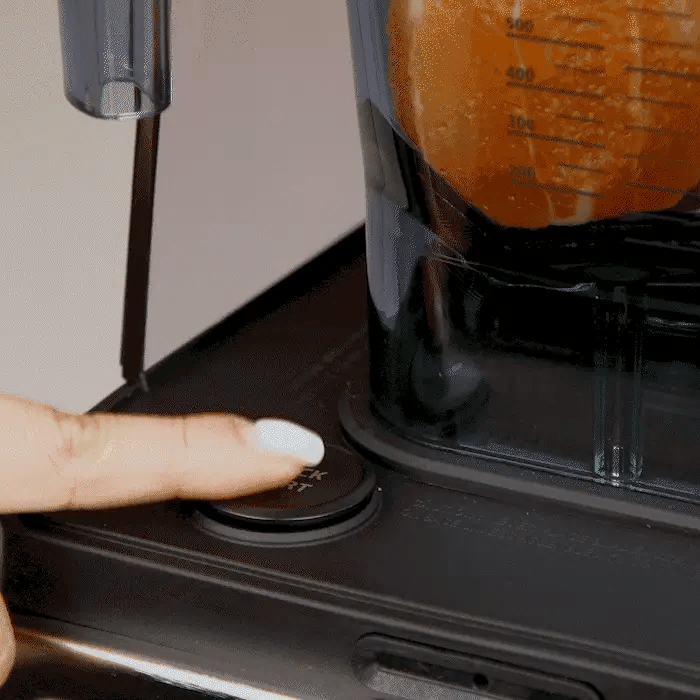 Kuvings CB1000 vákuumos turmixgép – a vákuum funkció gomb megnyomása, a kancsóban narancsdarabokkal.