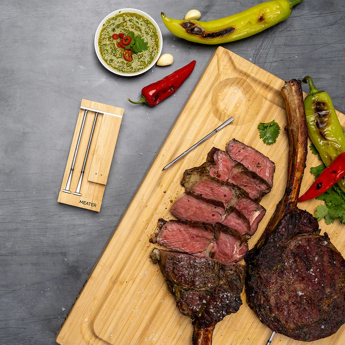 Szeletelt Tomahawk steak MEATER vezeték nélküli húshőmérővel és fűszeres mártogatóssal tálalva