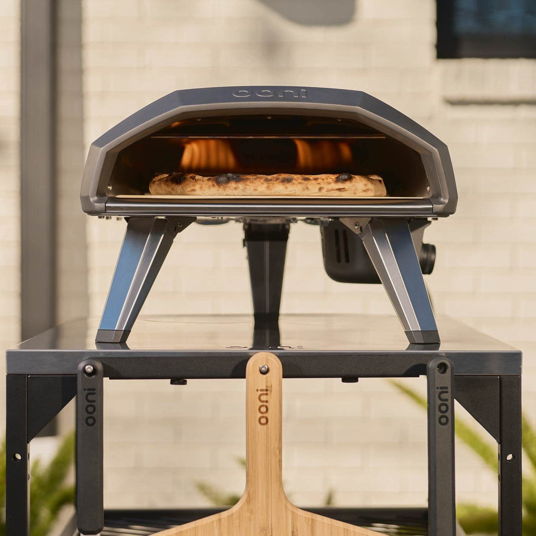 Ooni Koda 2 pizzakemence kültéren, fa nyelű pizzalapátokkal felszerelve

